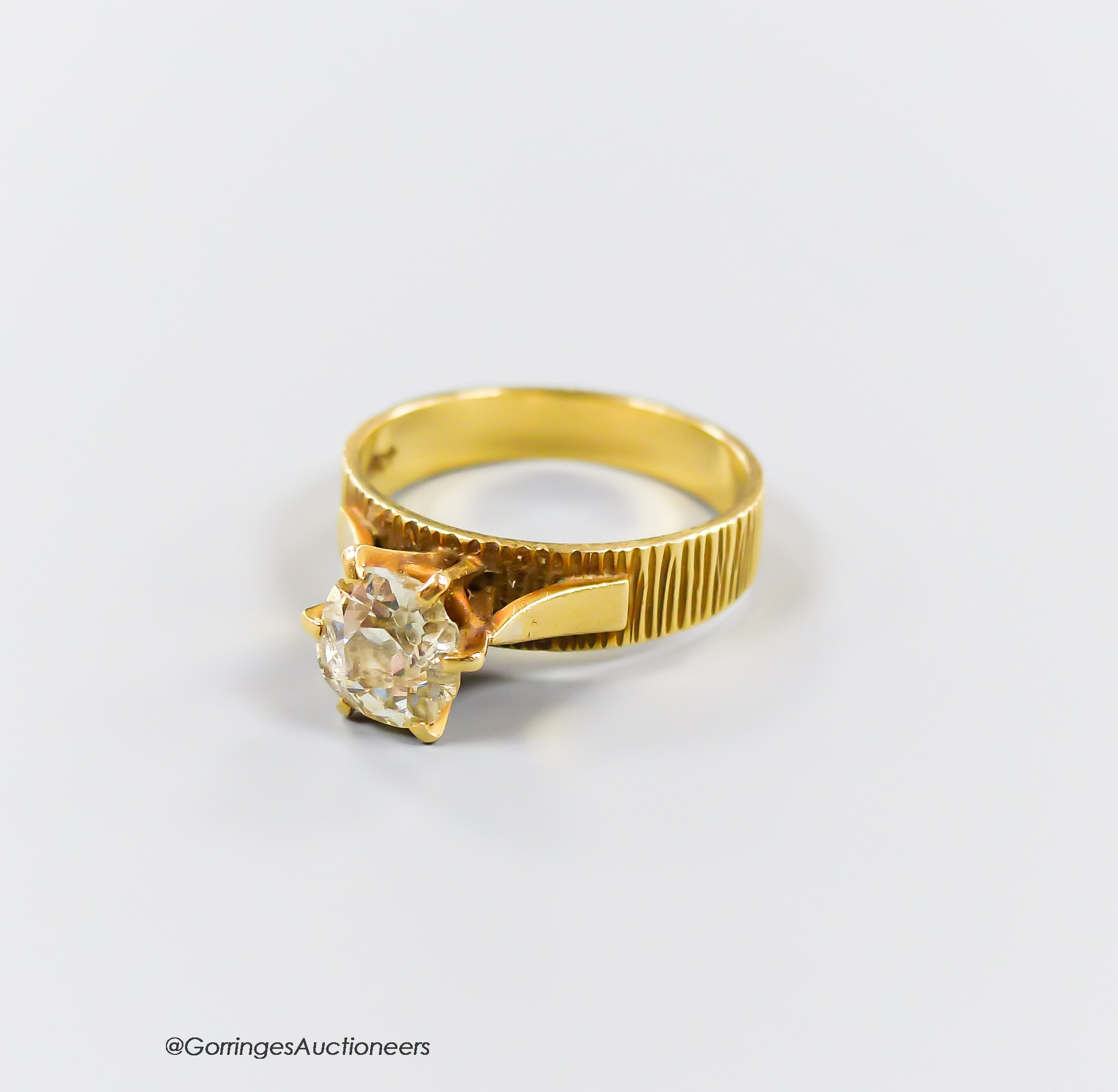 A textured 18ct and solitaire diamond ring, size Q, gross weight 5.4 grams, the stone diameter 7.5mm, (chipped).